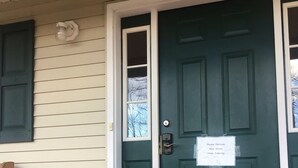 A green door with a sign requesting visitors to remove their shoes upon entering.