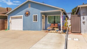 A single-story house with a garage, a covered porch, and a small garden area with rocks and plants. - Bring Your Bag And Get Ready To Relax!! (Oxnard)