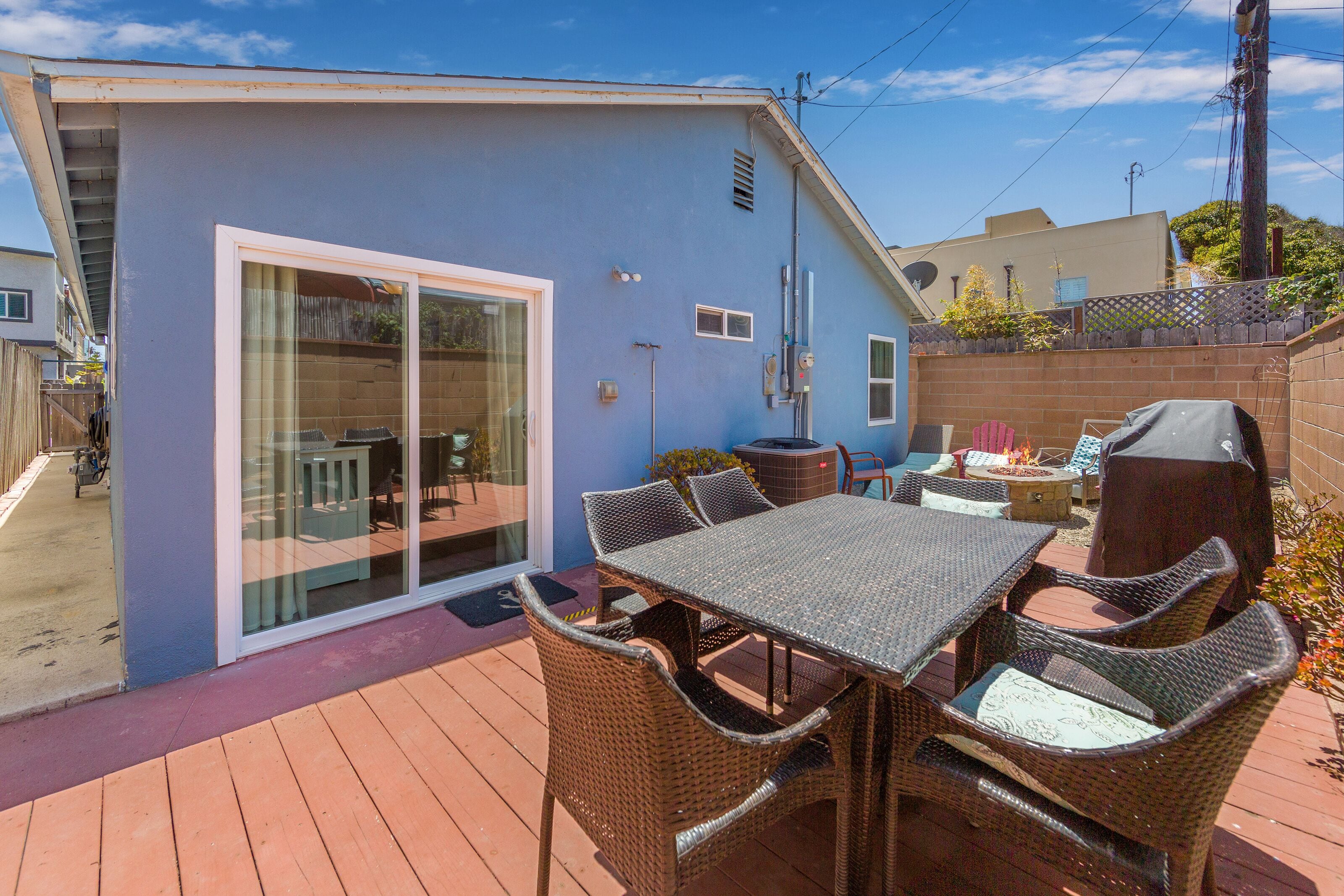 A patio with a table and chairs, a barbecue grill, and a sliding glass door leading to a deck.