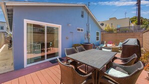 A patio with a table and chairs, a barbecue grill, and a sliding glass door leading to a deck. - Bring Your Bag And Get Ready To Relax!! (Oxnard)