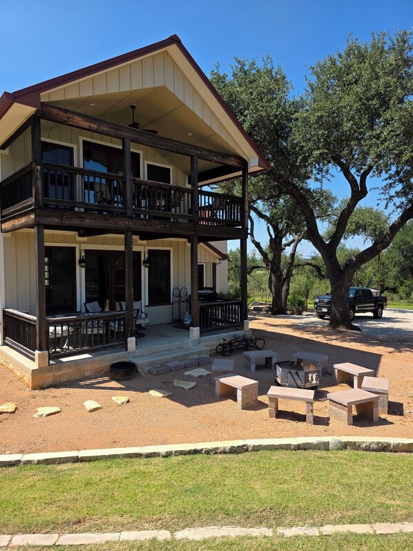 A two-story house with a balcony, outdoor seating, and a barbecue area.