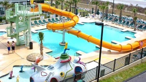 A water park with a large pool, a water slide, and a play structure.