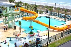 A water park with a large pool, a water slide, and a play structure.