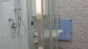 Un baño moderno con ducha envuelta en vidrio, un lavamanos blanco y una toalla azul colgada en la pared.