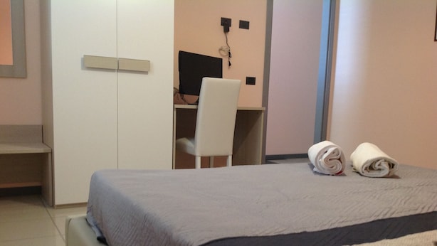 Un dormitorio con cama, escritorio y silla. Hay toallas sobre la cama.