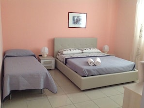 A bedroom with two single beds, a nightstand with a lamp, and a framed picture on the wall. - Limpiados Bed and Breakfast (Licata)