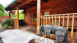 A wooden cabin with a 'Welcome' sign, a bear sculpture, and a 'Belkowski's' sign.