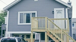 A two-story house with a front porch and a wooden staircase leading to the second floor.