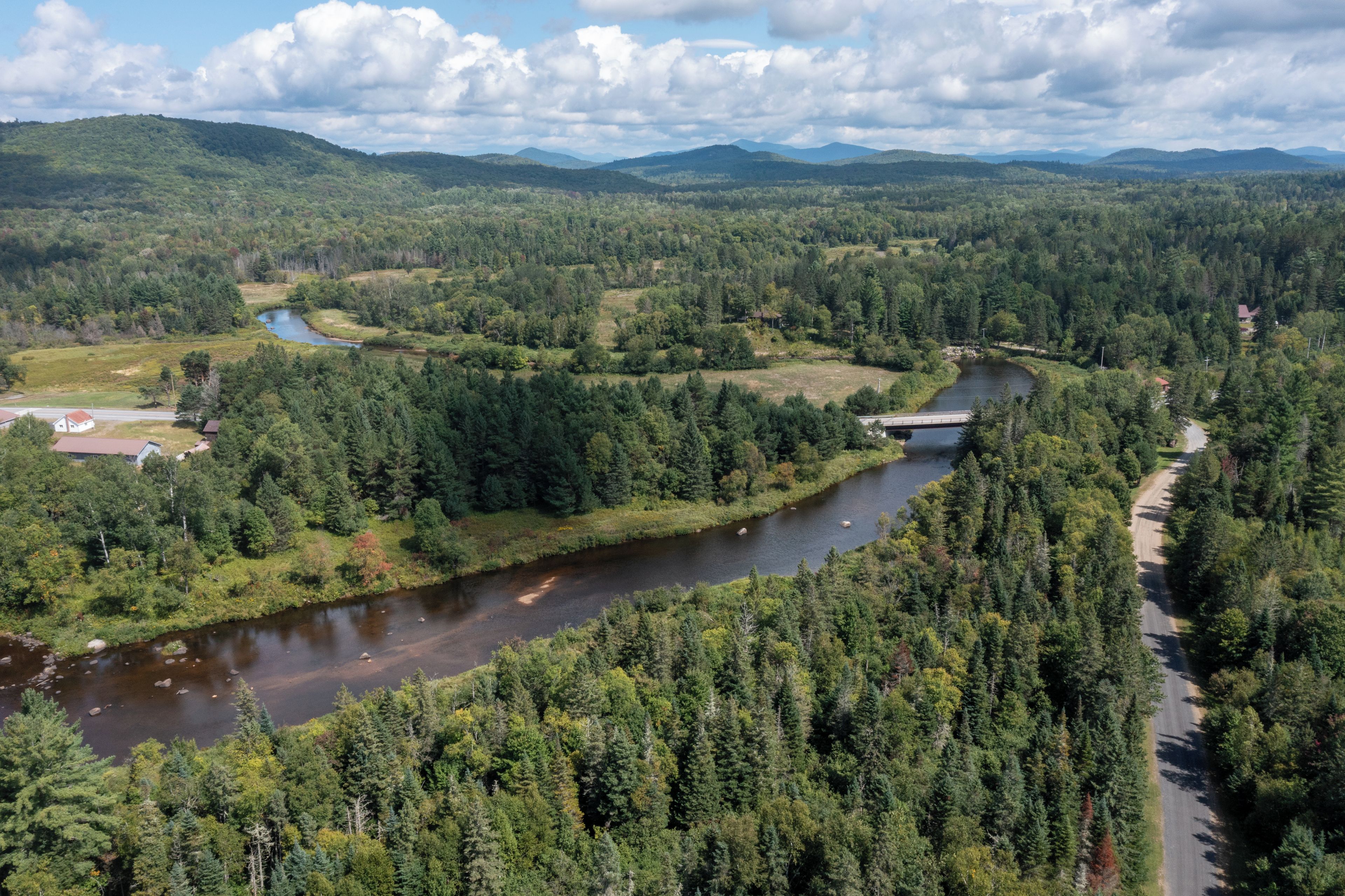 A river winding through a densely forested valley with a bridge crossing over the river.