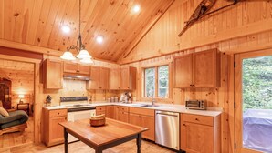 Interior de una cabaña de madera con cocina, que incluye estufa, lavamanos y lavavajillas.