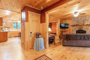 A wooden interior with a stone fireplace, a television, and a dining area. - Comfy Home in the Adirondacks, close to Gore Mnt, hiking & snowmoble trails (Indian Lake)