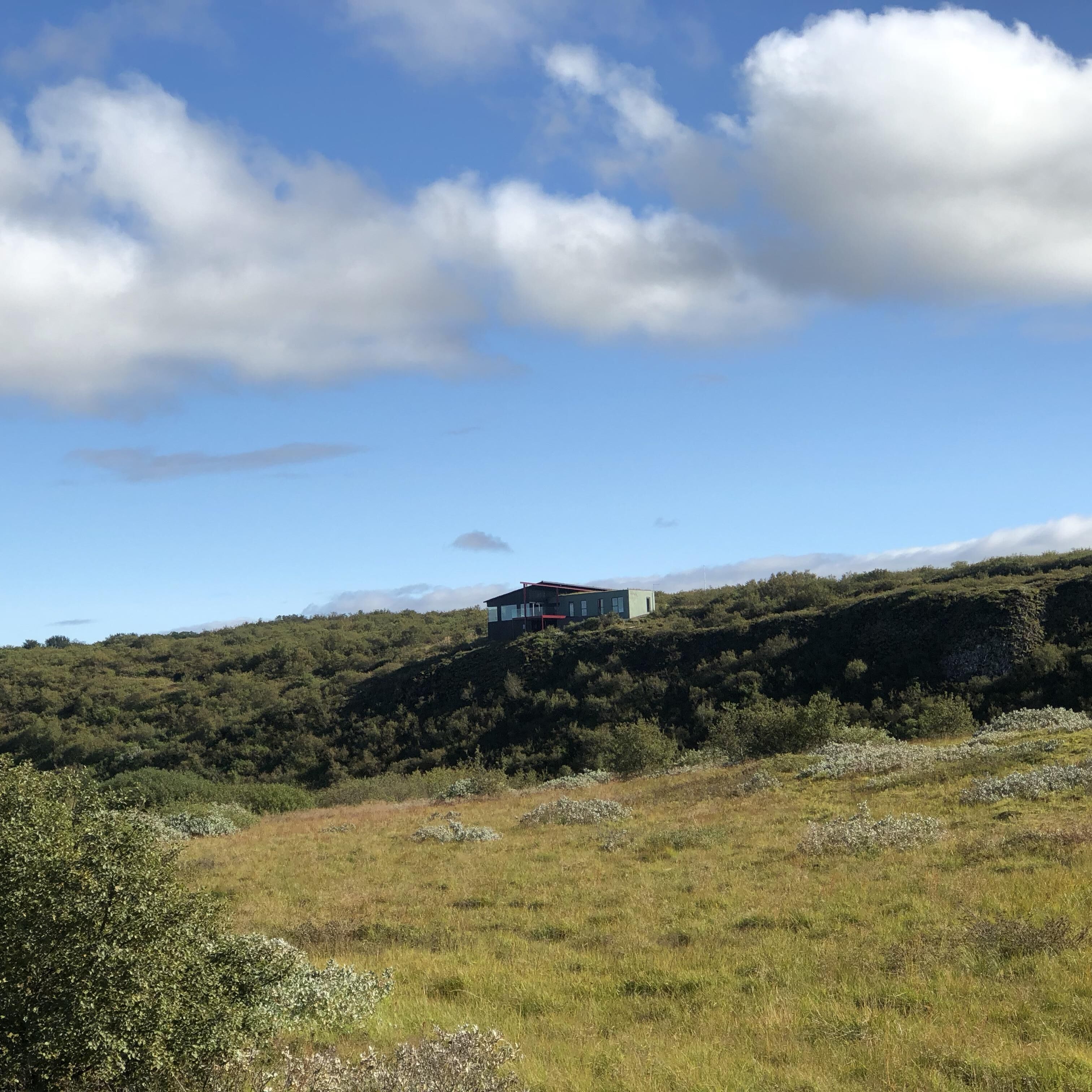Et moderne hus på en skråning under en klar himmel.