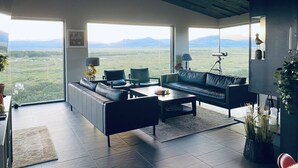 Un salon moderne doté d’une grande fenêtre donnant sur un paysage montagneux.
