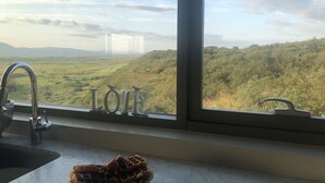 Une cuisine donnant sur un paysage verdoyant, avec une vue sur la ville en arrière-plan.