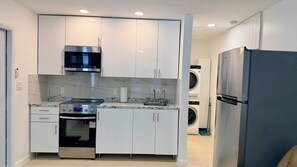 Una cocina moderna con armarios blancos, una estufa de acero inoxidable, un microondas y un refrigerador.