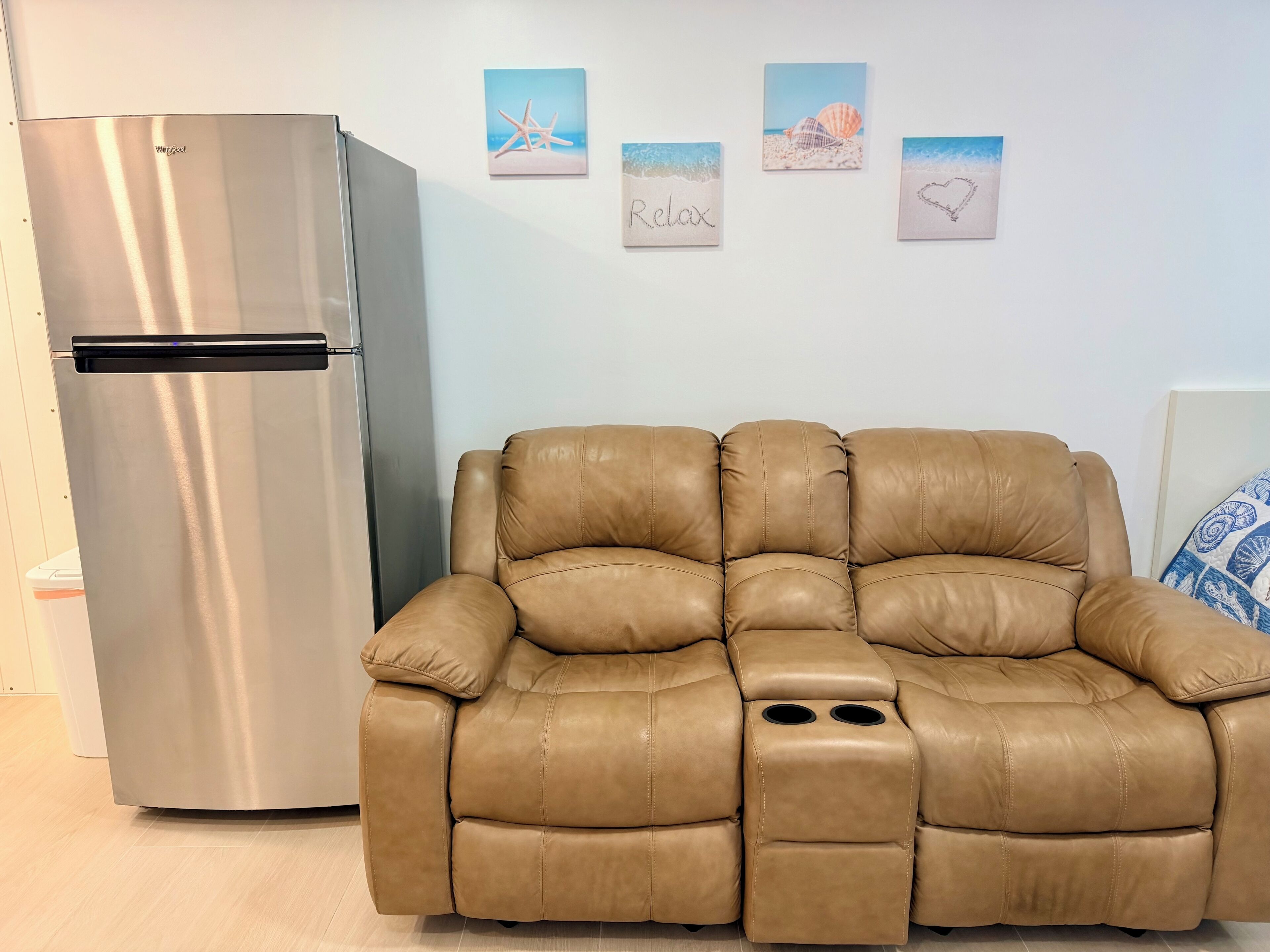 Una sala de estar moderna con un sofá de cuero y un refrigerador de acero inoxidable.