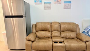Un soggiorno moderno con un divano in pelle e un frigorifero in acciaio inossidabile.