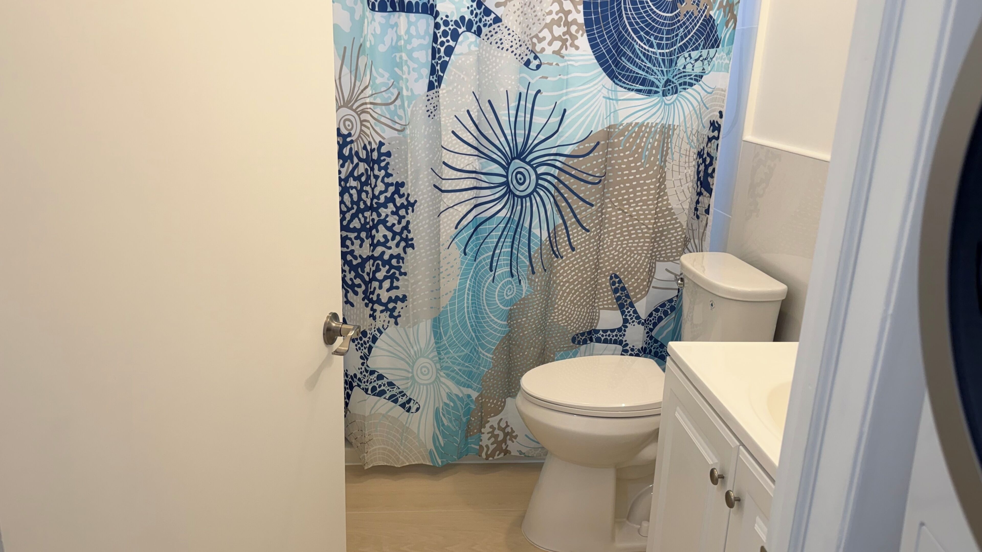 Ein Badezimmer mit Toilette, Waschbecken und einer Duschkabine mit Meeresmotiven.