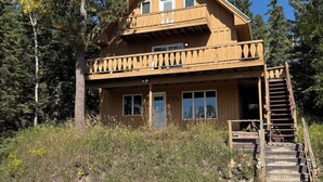 A two-story wooden cabin with a balcony, surrounded by trees and a gravel path. - Double Diamond Lodge on Terry Peak--Your outdoor adventures await!! (Lead)