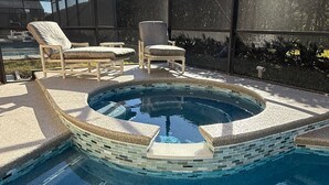 A swimming pool with a tiled edge, surrounded by lounge chairs and a covered area. - Ashland Palms: Modern pool home, close to Disney on Glenbrook Resort  (Clermont)