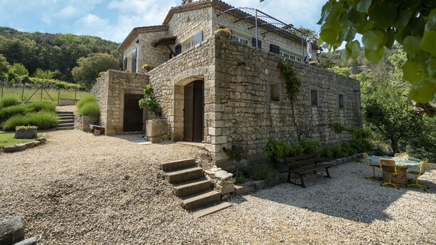 A stone building with a rustic charm, featuring a stone staircase leading to a wooden door, surrounded by gravel and greenery. - Holiday Home in Montclus near river (Montclus)