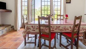 A dining area with a table set for four, surrounded by wooden chairs with red cushions. - Holiday Home in Montclus near river (Montclus)