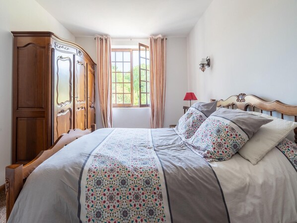 Un dormitorio con una cama grande, un armario de madera y una ventana con cortinas.
