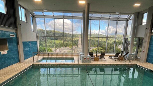 Una piscina interior con vistas despejadas a un paisaje montañoso a través de amplios ventanales.