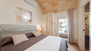 Une chambre à coucher avec un lit, une table de chevet, une lampe, une armoire et une fenêtre avec des rideaux.
