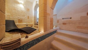 Un espace spa agrémenté d’un mur en pierre, d’une baignoire et d’une table de massage.