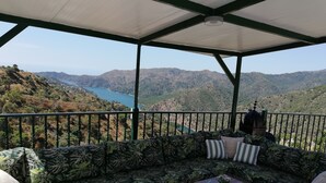 Un espacio de estar al aire libre techado con vistas a un lago y montañas.