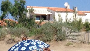 Una casa con antena parabólica, rodeada de vegetación y una valla de madera.