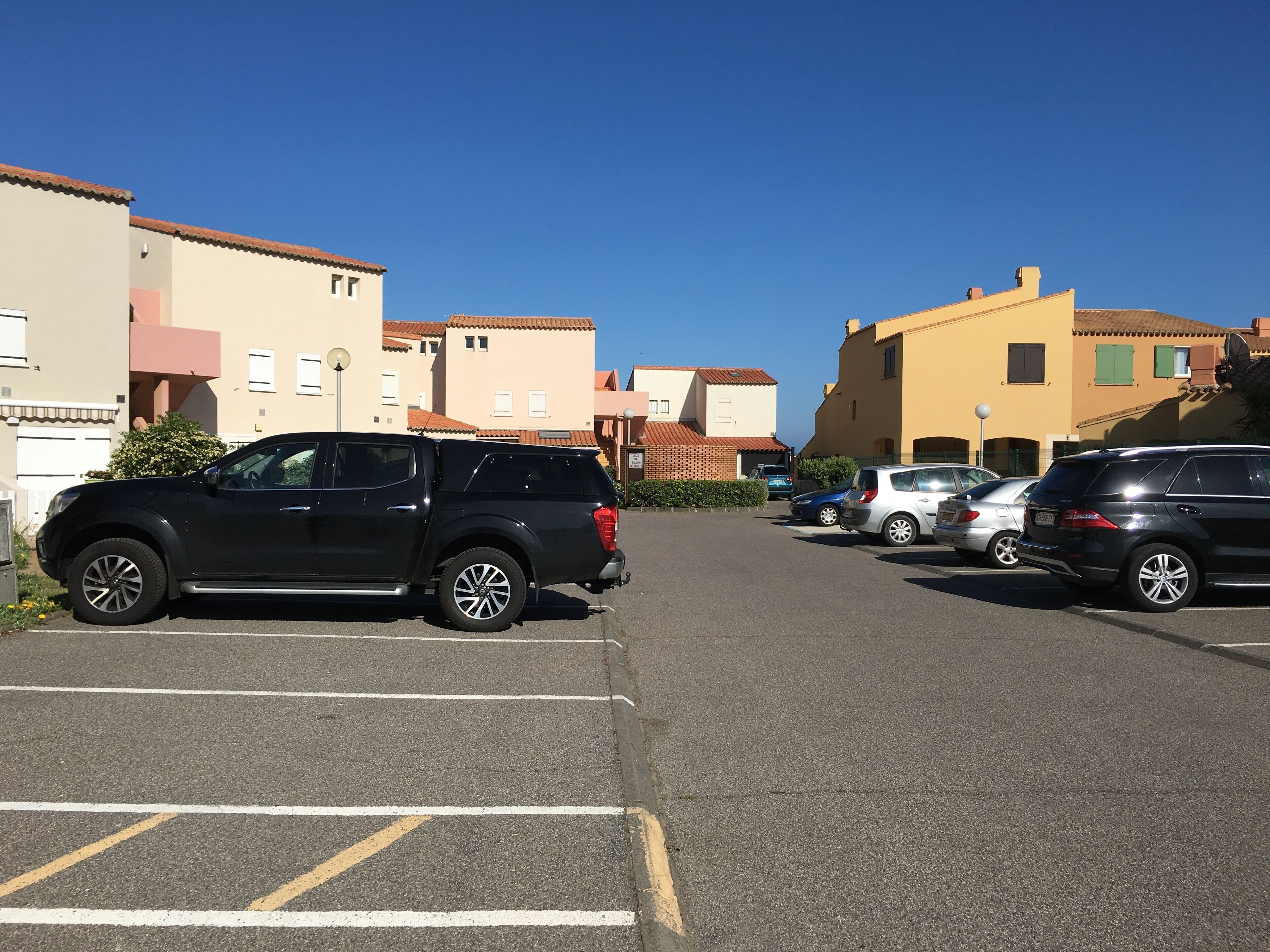 A parking lot with several cars, including a black SUV and a silver car.