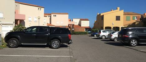 A parking lot with several cars, including a black SUV and a silver car.