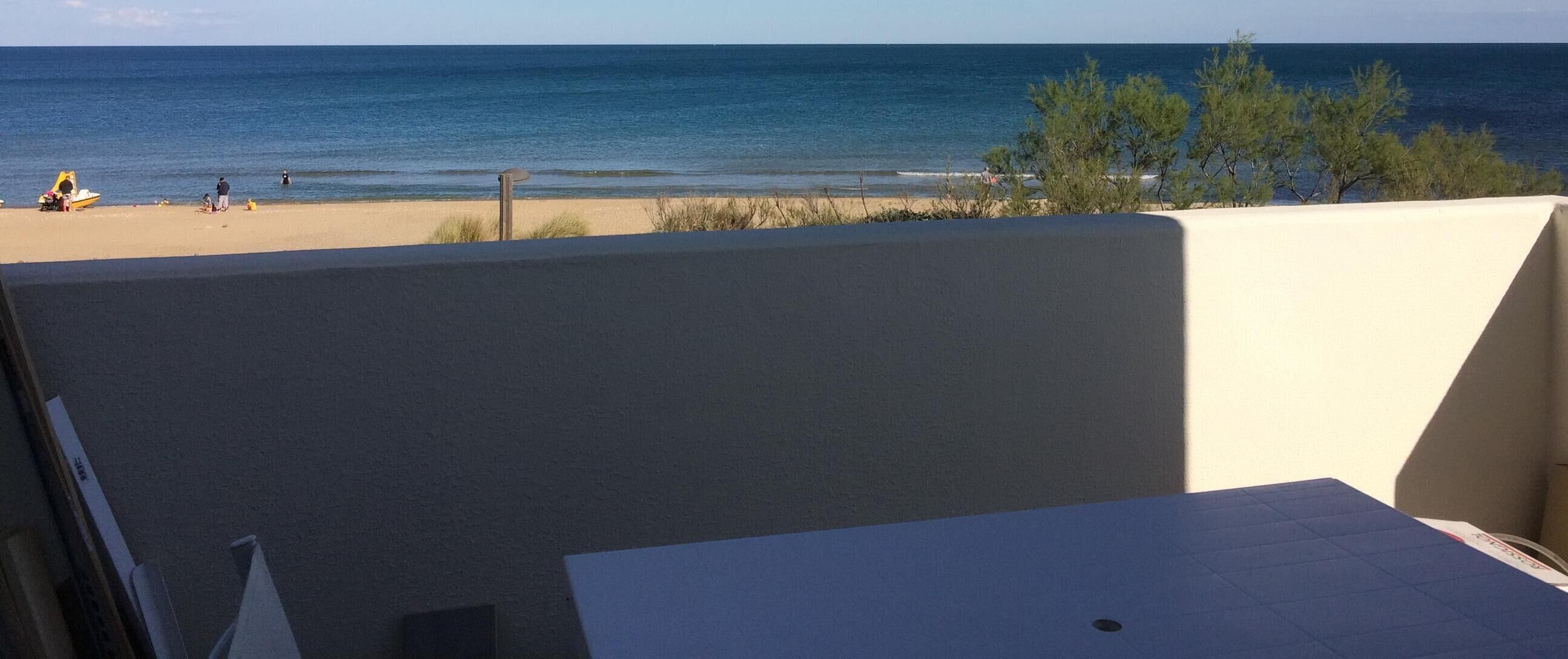 A balcony with a view of the beach and ocean.