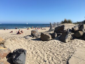 A sandy beach with large rocks and a wooden fence.