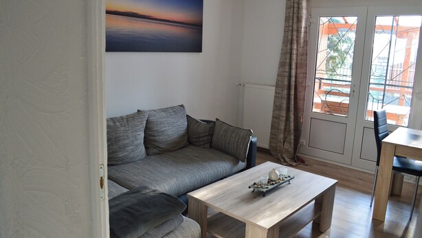 A living room with a sofa, a coffee table, and a painting of a sunset.