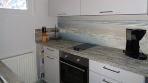 A kitchen with white cabinets, a stainless steel oven, a coffee maker, and a window with a view of the outdoors.