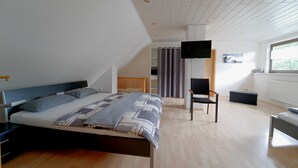Une chambre à coucher moderne avec un lit, une chaise, un téléviseur et une fenêtre.