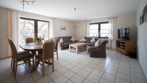 Un salon comprenant un coin repas, deux canapés, une table basse et un téléviseur.