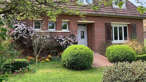 Una casa a due piani in mattoni con una porta d'ingresso, tre finestre e un piccolo portico.