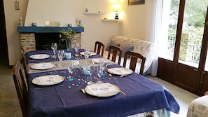 Une table à manger dressée pour six personnes, avec une nappe bleue, des assiettes et des verres.