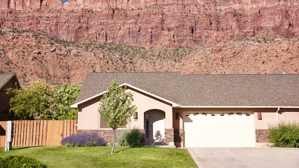 A single-story house with a garage, surrounded by a wooden fence, and a small tree in the front yard. - Westwater - Spacious 3 Bed, 2.5 Bath Moab House - Sleeps 8 (Moab)