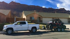 A white pickup truck towing a Polaris ATV trailer parked in front of a house with a mountain backdrop. - Westwater - Spacious 3 Bed, 2.5 Bath Moab House - Sleeps 8 (Moab)