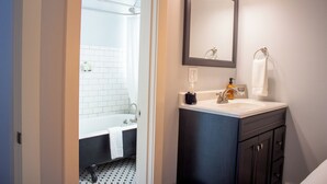 A bathroom with a bathtub, a sink, and a mirror.