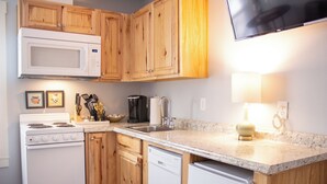 A kitchen with wooden cabinets, a microwave, a stove, a dishwasher, and a sink.