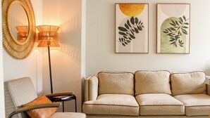 A living room with a sofa, a chair, a lamp, and two wall art pieces.