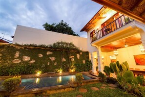 Tropical courtyard and 40' pool at dusk.  Master bedroom balcony overlooks pool