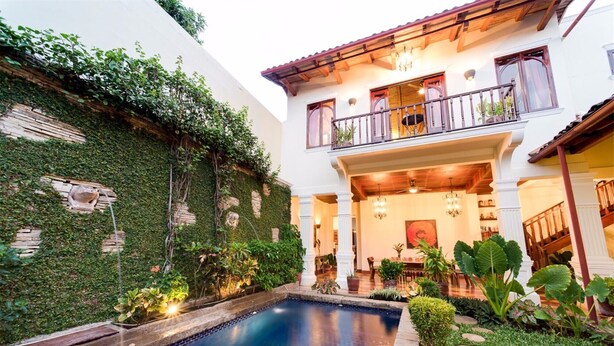 Ein zweistöckiges Haus mit Schwimmbad, Balkon und Garten.