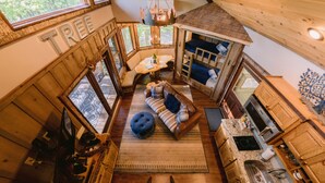 A cozy cabin interior with a loft bedroom, a dining area, and a kitchen. - Canopy Blue Luxury Treehouse *hot tub, fire pit, swing bed, amazing views* (Blue Ridge)